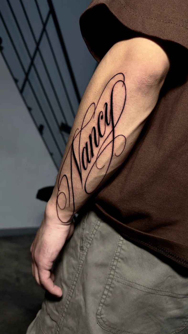 Lettering cursivo 'Nancy' en el antebrazo